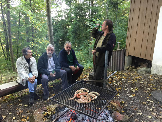 Mitglieder sitzen und stehen am Grill bei der Jägerhütte